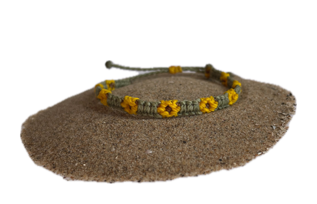 Geknoopte armband met zonnebloemen. De bloem is geel en het bandje is groen.