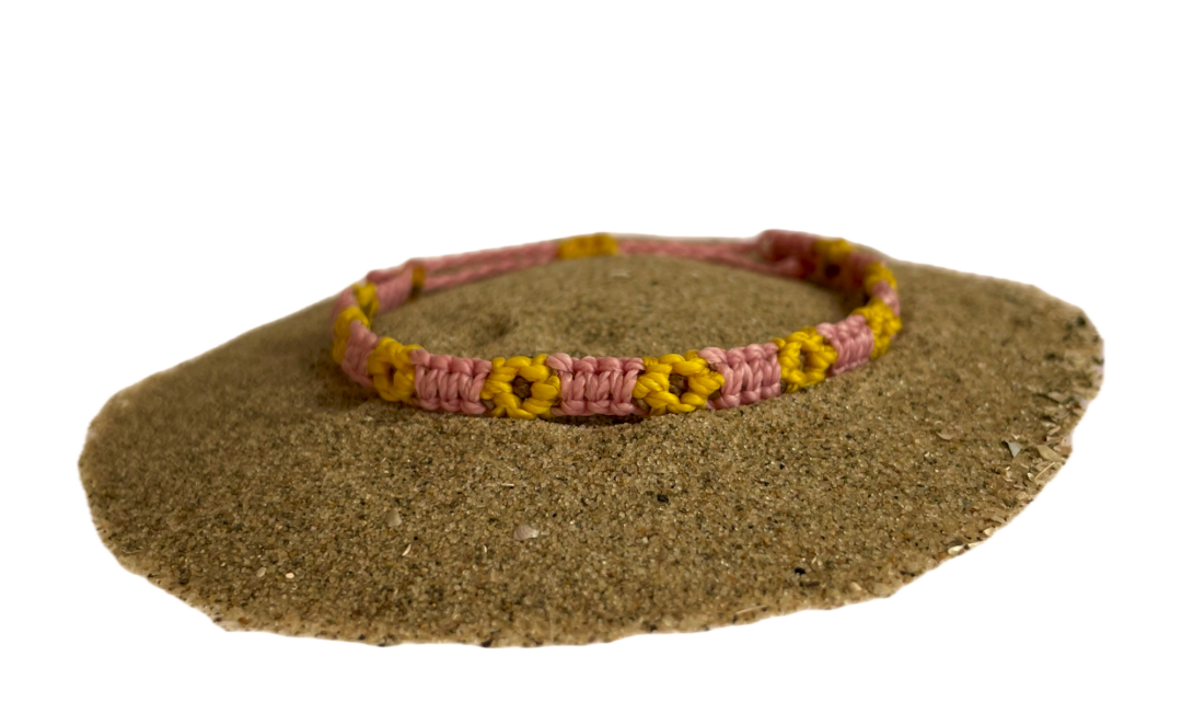 Geknoopte armband met zonnebloemen. De bloem is geel en het bandje is roze.