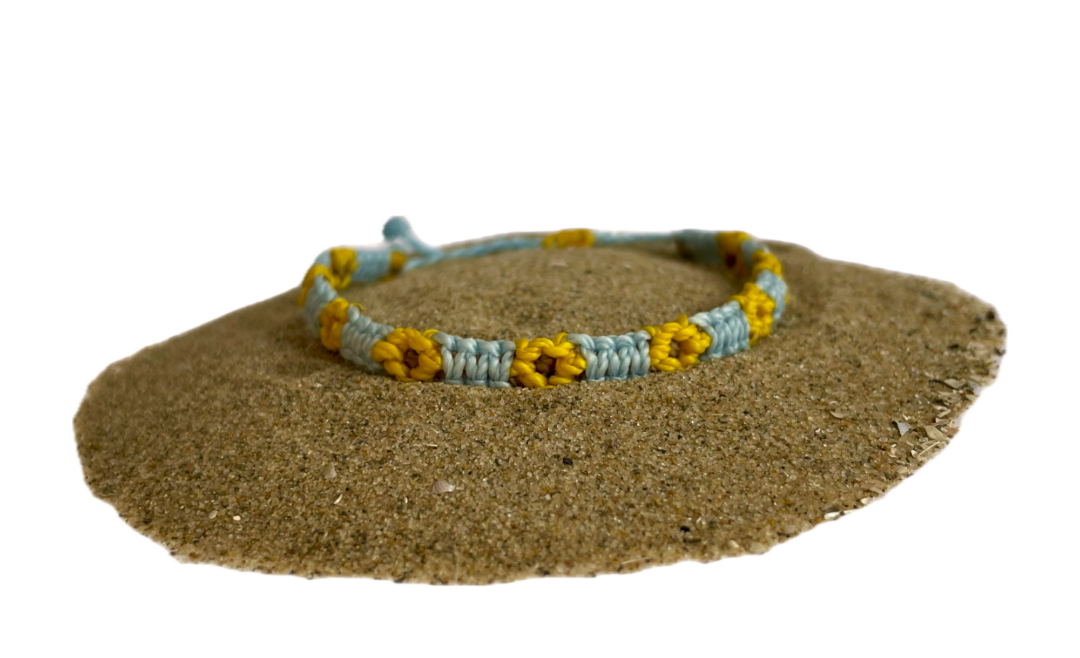 Geknoopte armband met zonnebloemen. De bloem is geel en het bandje is blauw.