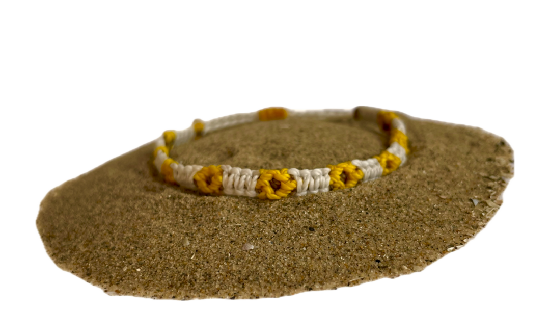 Geknoopte armband met zonnebloemen. De bloem is geel en het bandje is wit.