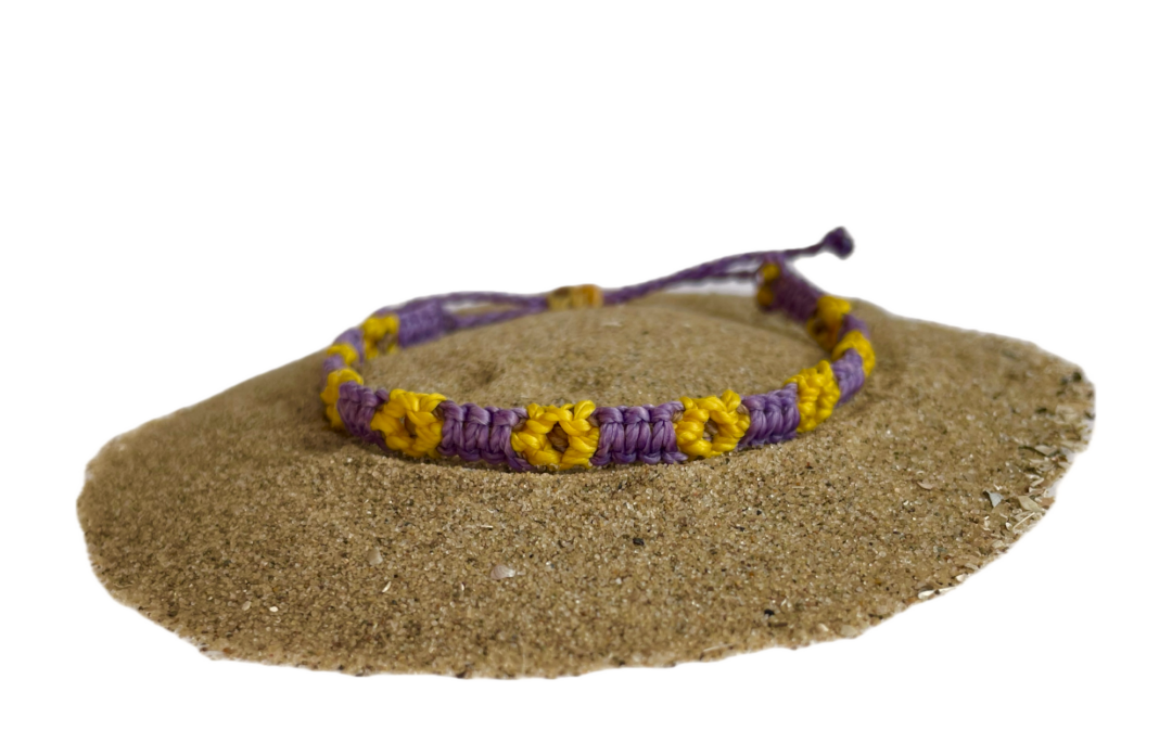 Geknoopte armband met zonnebloemen. De bloem is geel en het bandje is paars.